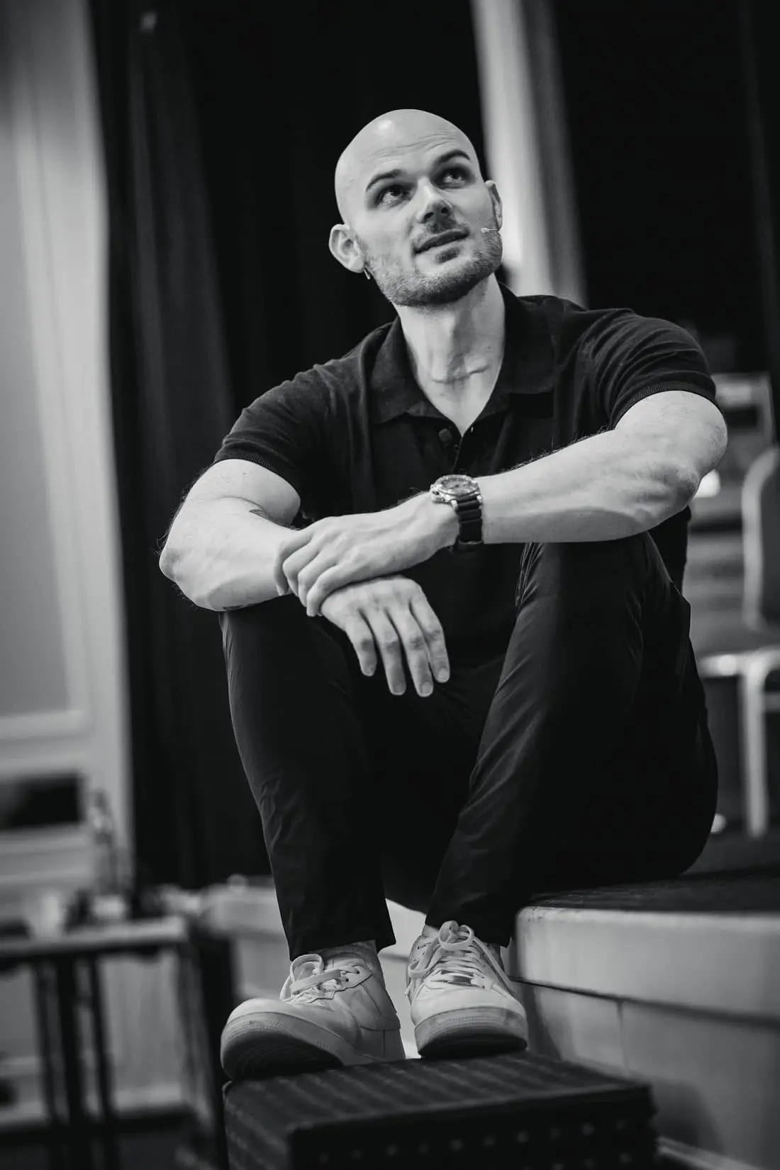 Fabian Schaub sitzt auf einer Bühnenkante, den Blick nach oben