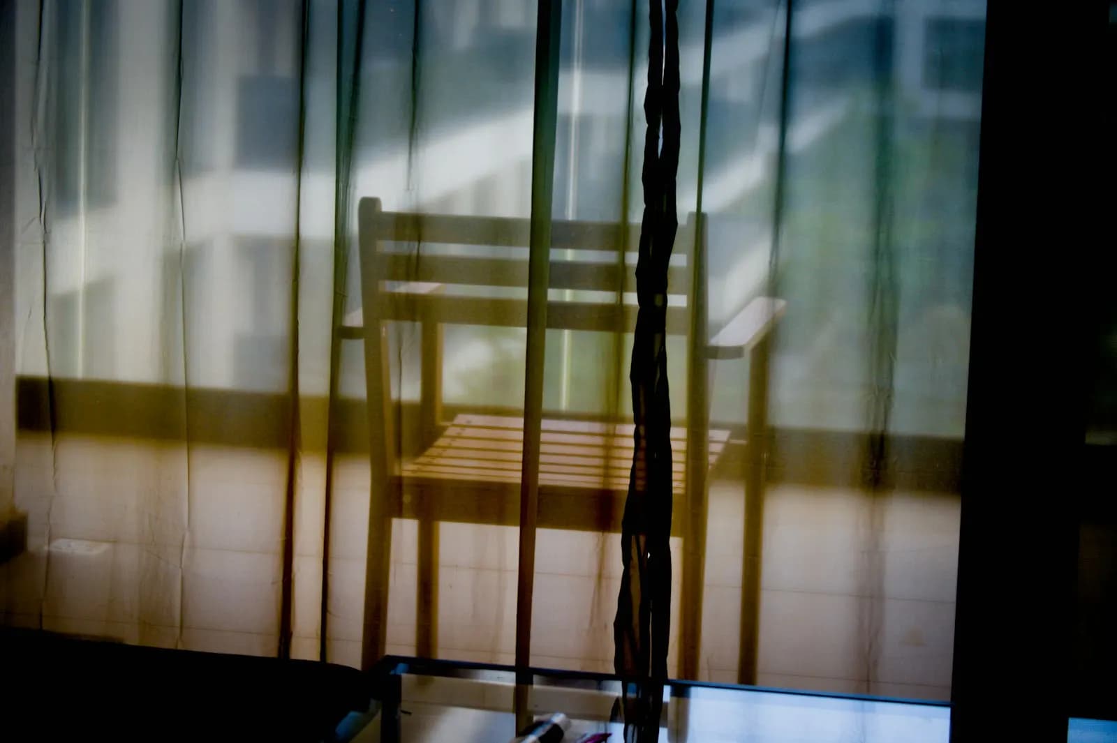 Ein leerer Stuhl vor einem Fenster im gedämpften Licht, ohne Menschen im Bild.