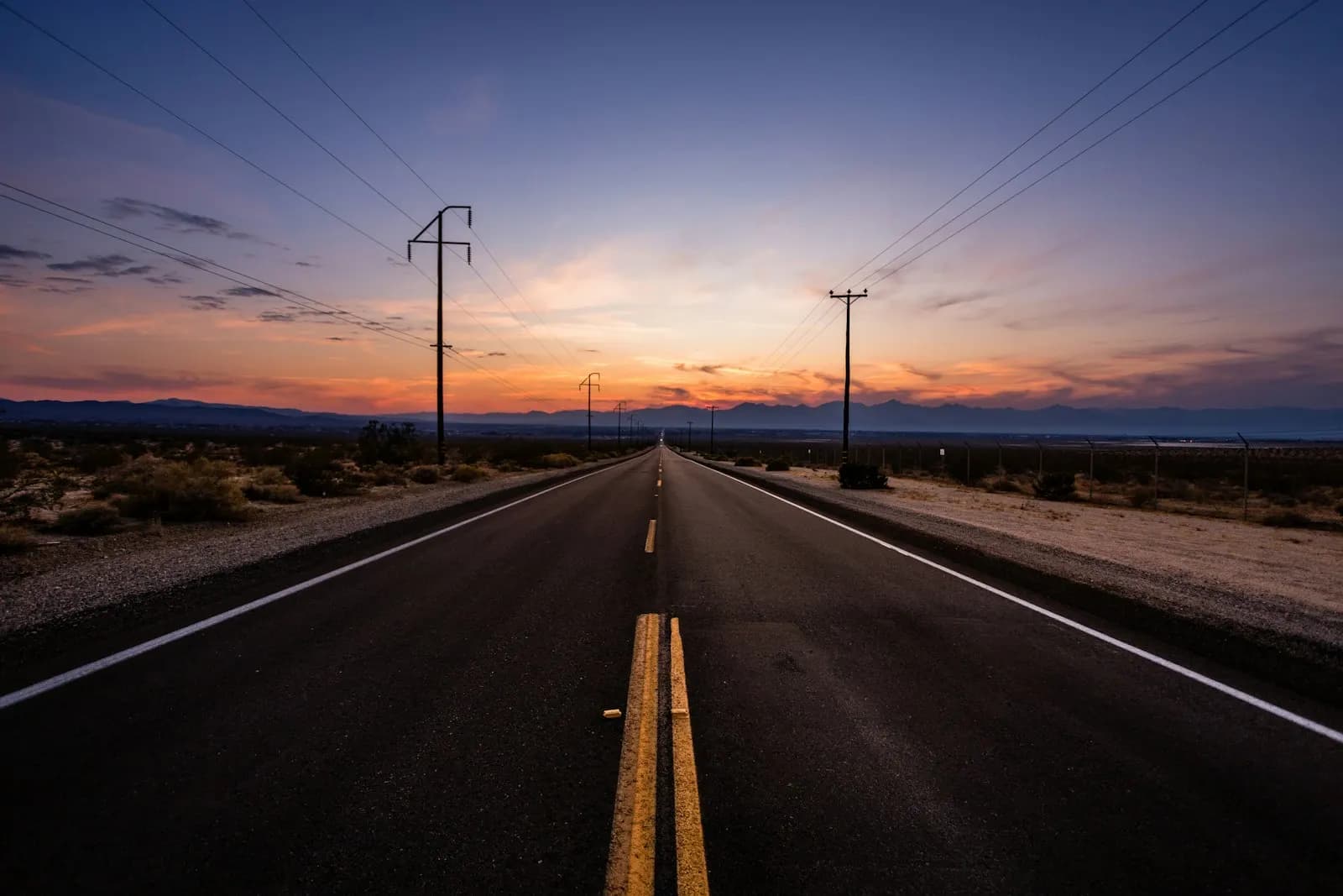 Eine leere Straße, die in der Abenddämmerung am Horizont verschwindet